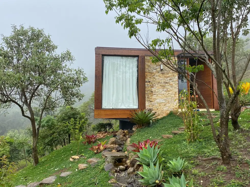 Fachada em pedra e madeira integrada ao terreno — NS Engenharia
