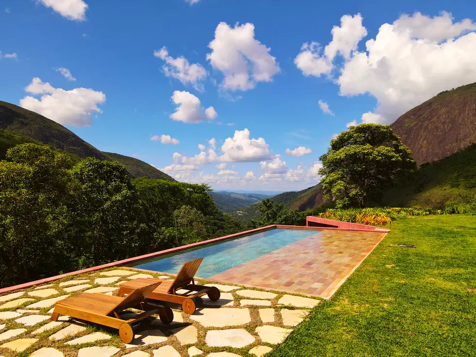 Piscina com deck em pedra e vista para as montanhas — NS Engenharia